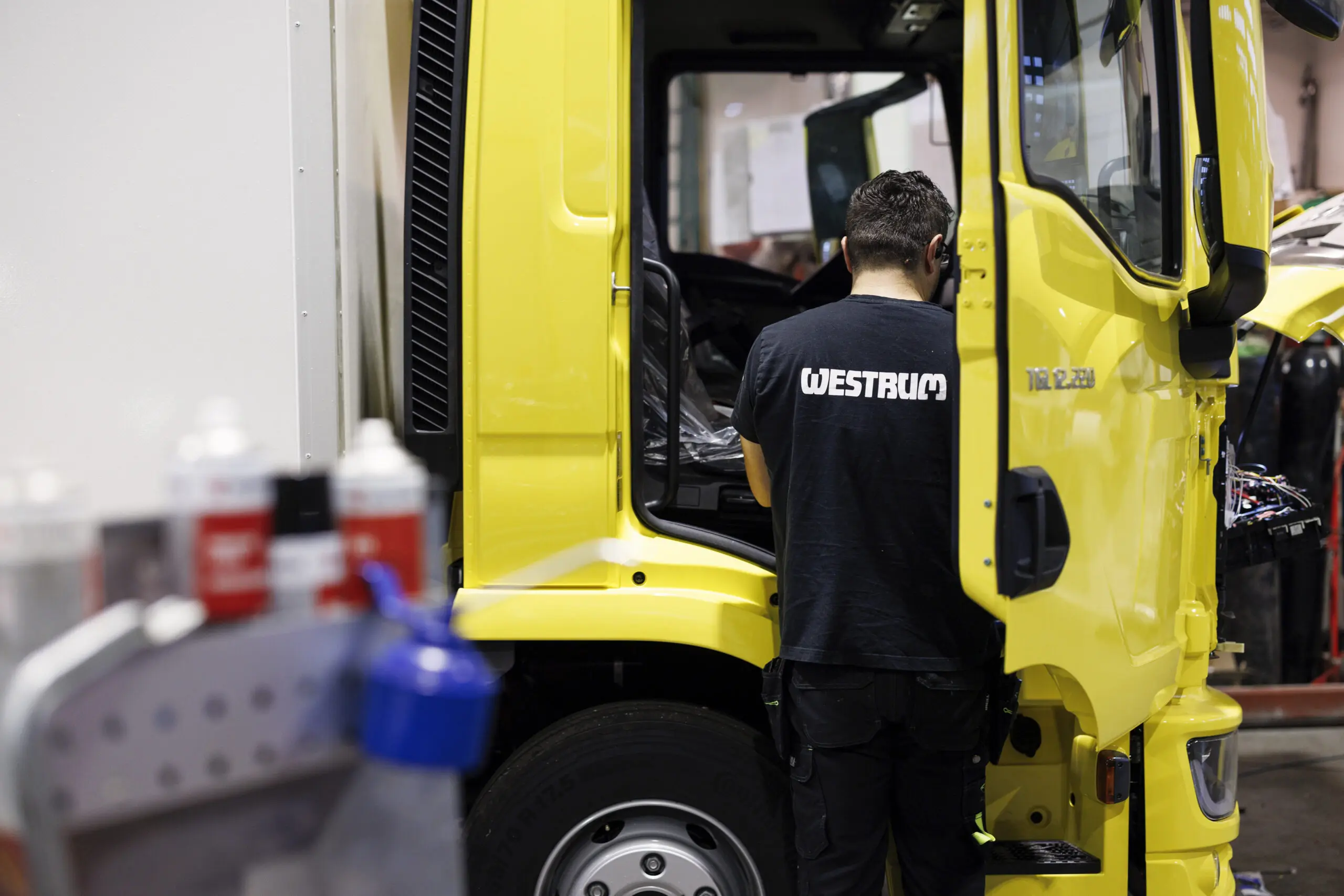bildet viser en ansatt hos westrum som jobber med en gul lastebil